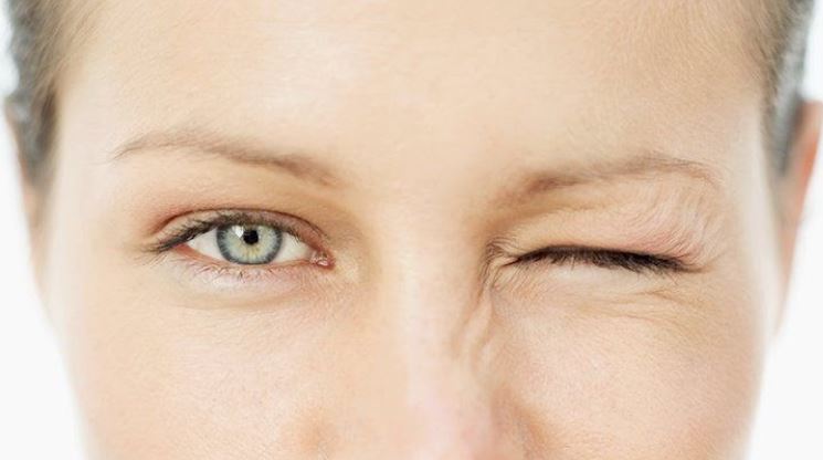A woman's face with one eye open and the other screwed shut.