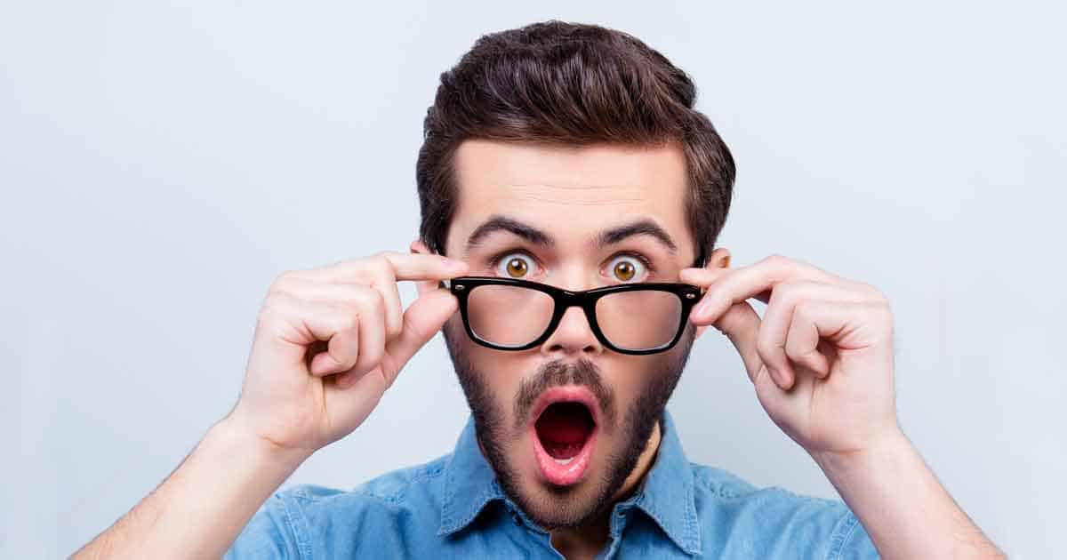رجل يخفض نظارته وعيناه متّسعتان وفمه مفتوح.